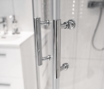 Close up photo of silver door handles on custom glass shower doors