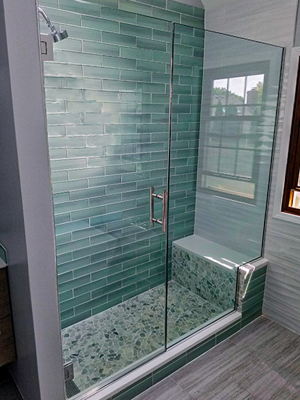 This photo shows a frameless shower door in a stylish bathroom with gray laminate flooring